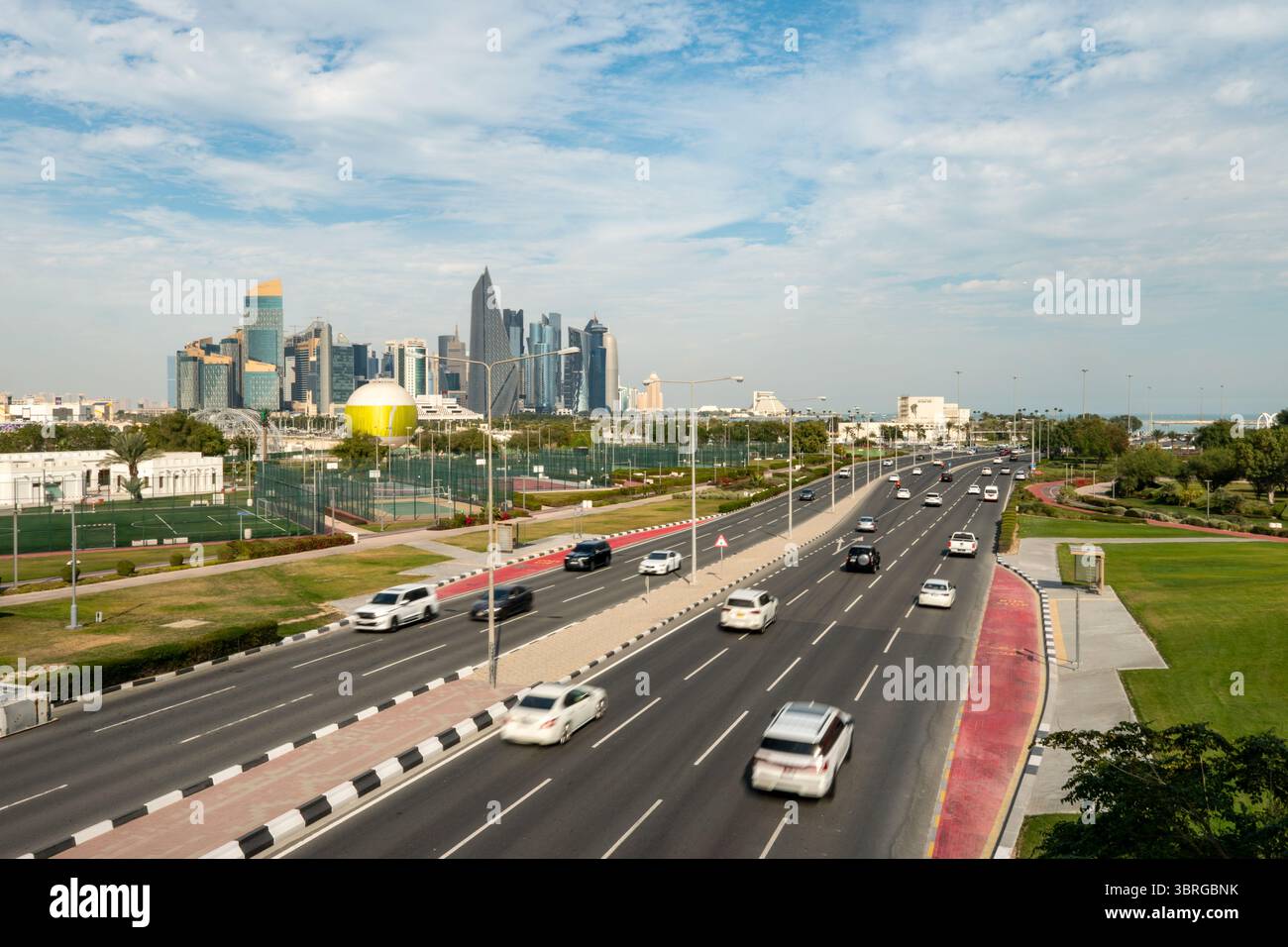 A road in a megalopolis against the backdrop of skyscrapers in Doha Qatar. Cars are driving along the highway. Stock Photo