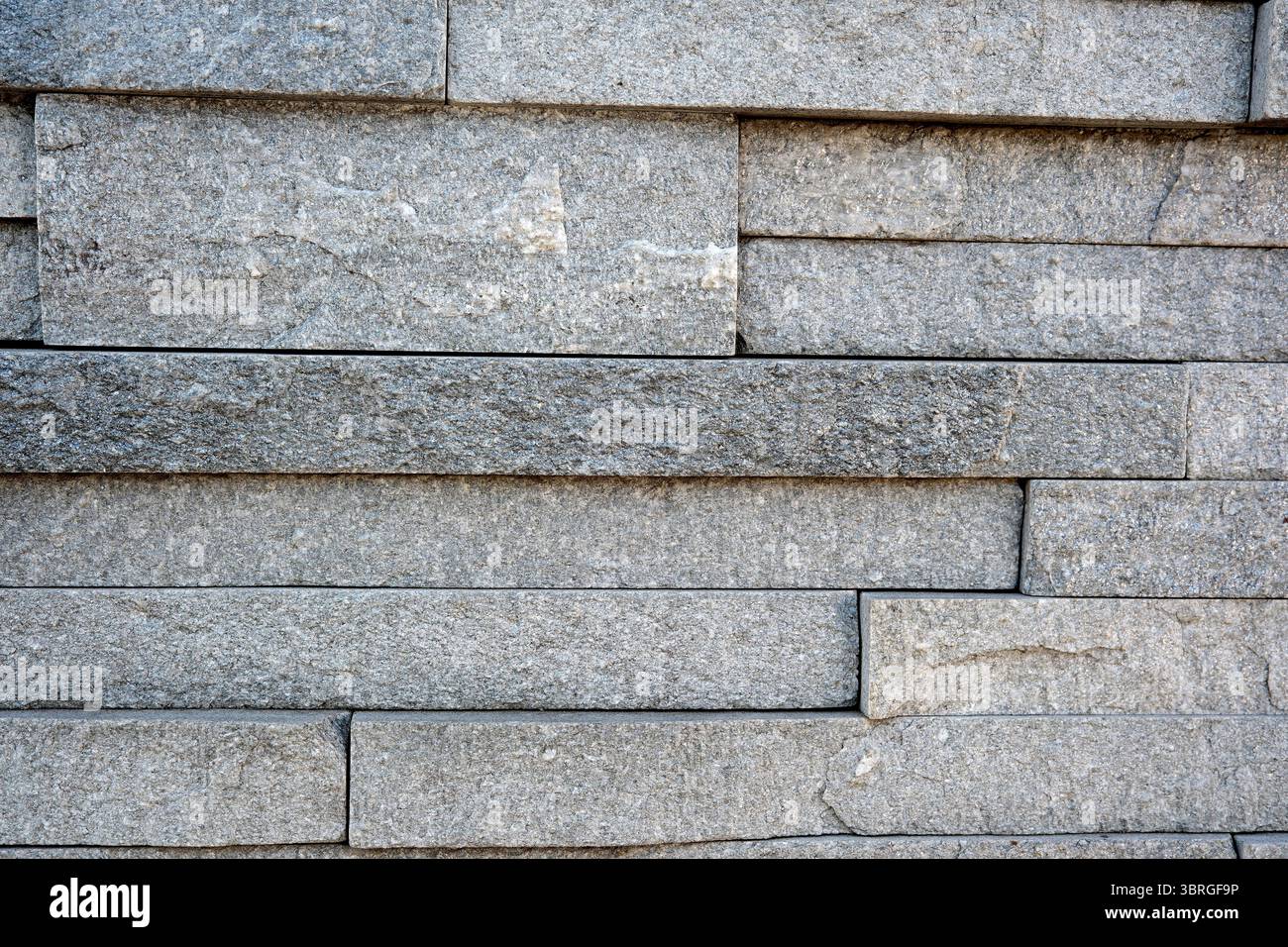 Gray stone blocks create a striking textured wall surface in daylight. Stock Photo
