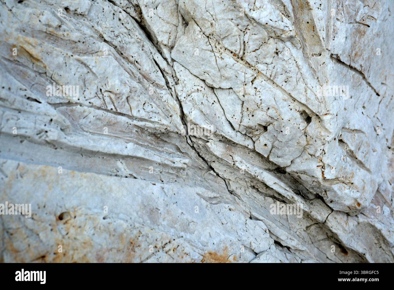 Detailed textures and cracks adorn a large, weathered rock formation. Stock Photo