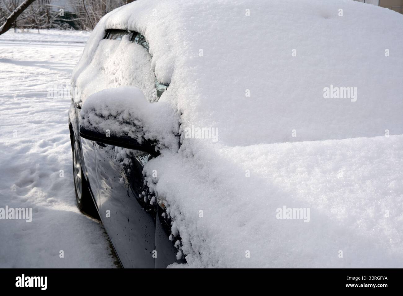 A parked car is completely covered in fresh white snow during winter. Stock Photo