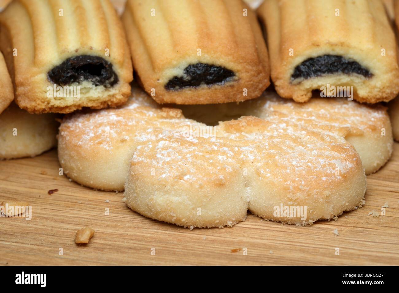 A delightful arrangement of freshly baked treats lies on a rustic wooden surface, featuring golden pastries and soft cookies, inviting all to enjoy th Stock Photo