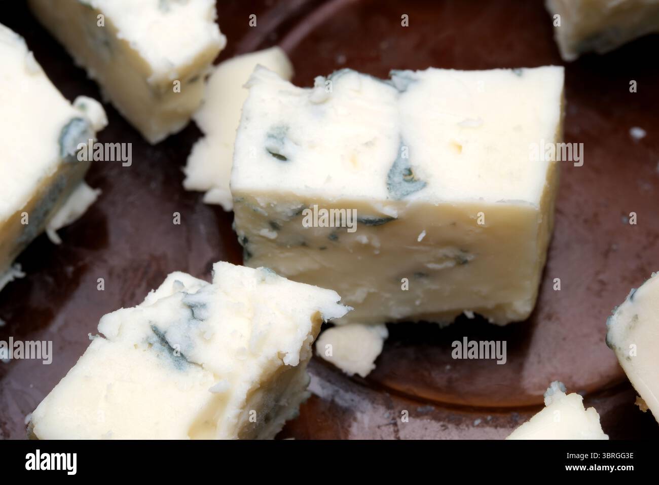 Delight in the creamy consistency and intriguing marbling of artisan blue cheese, presented on a rustic wooden platter, inviting cheese lovers to savo Stock Photo