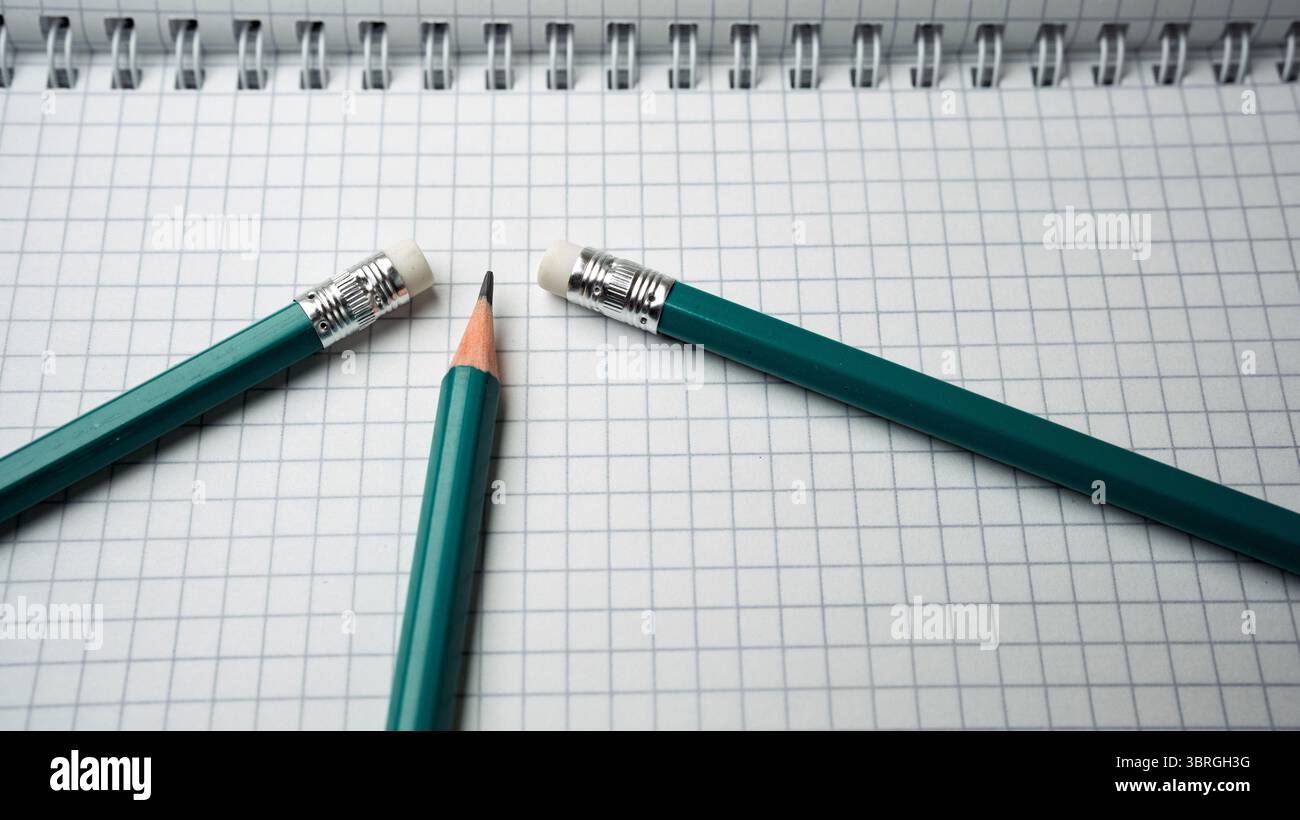 Teal pencils are artistically placed on a grid-patterned notebook. Stock Photo