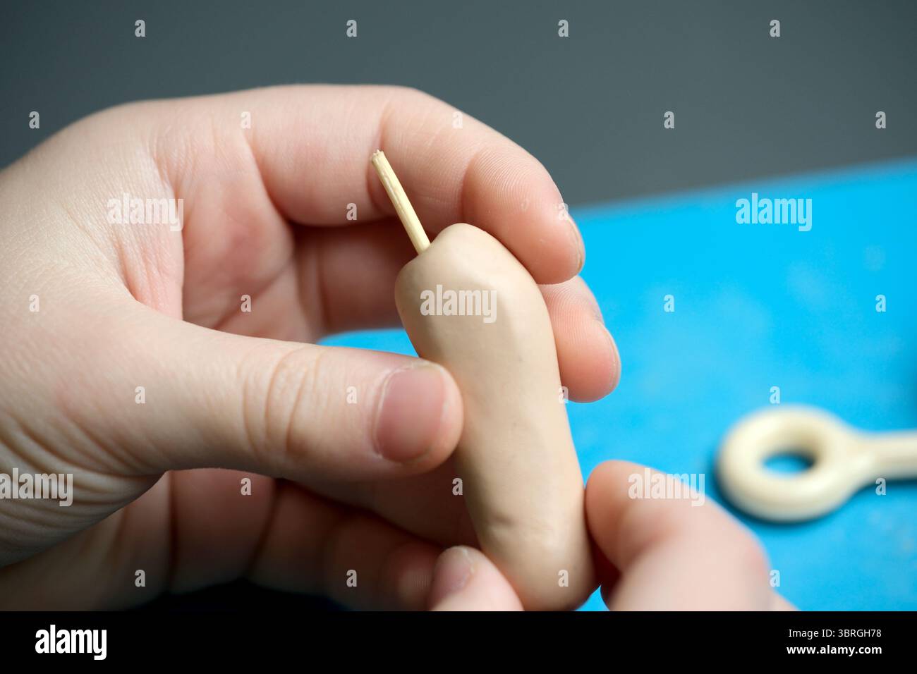 Hands mold soft clay into a creative shape at a workspace with tools. Stock Photo