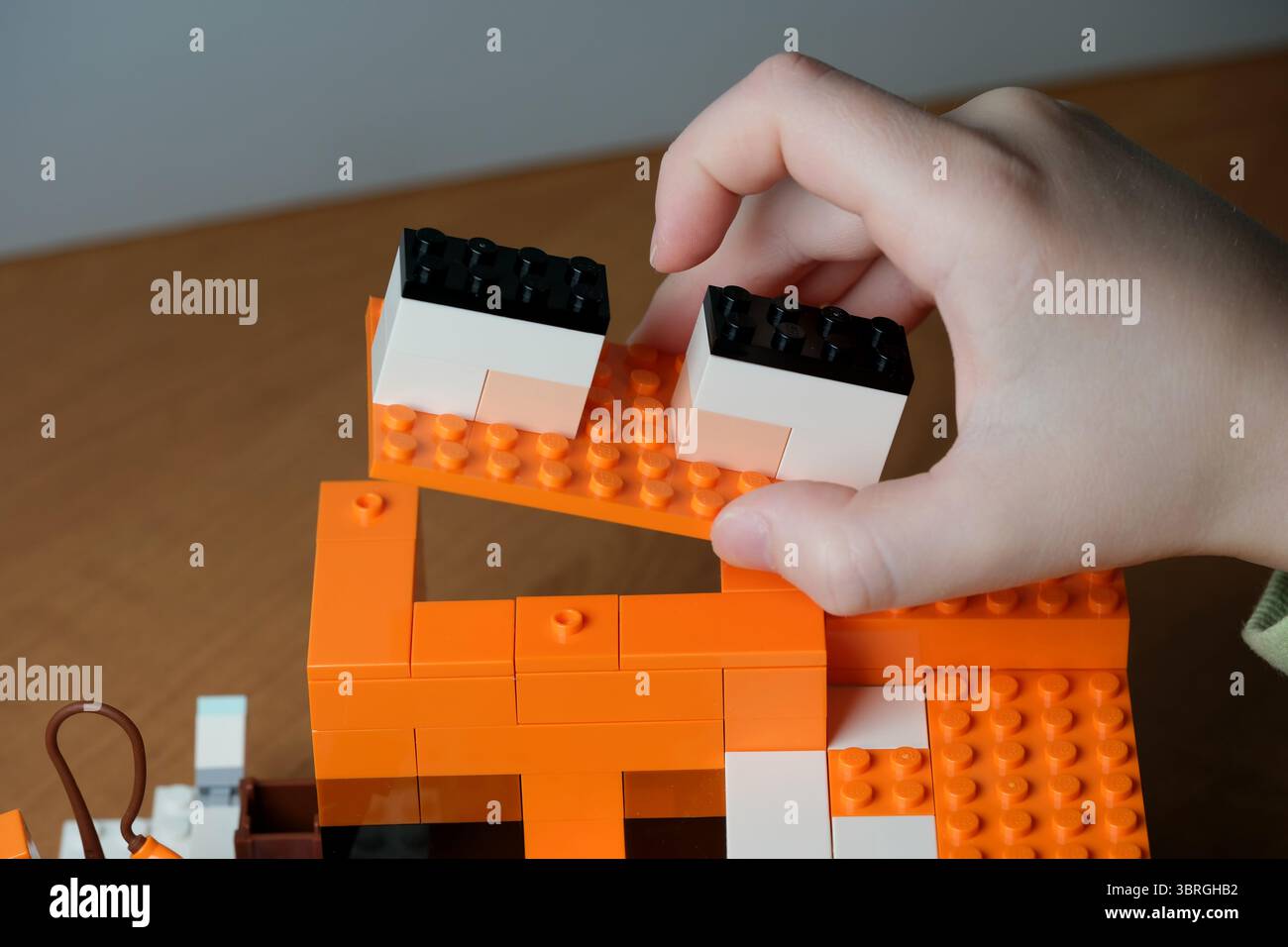 Engaging in a hands-on creative project using orange building blocks. Stock Photo