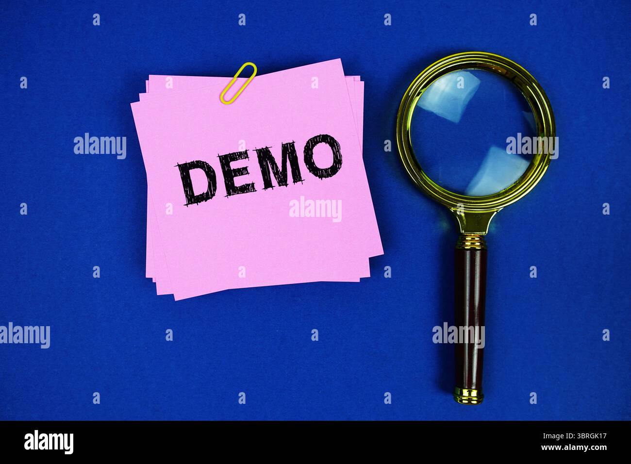 Demo text on sticky note with magnifying glass on navy blue background ...