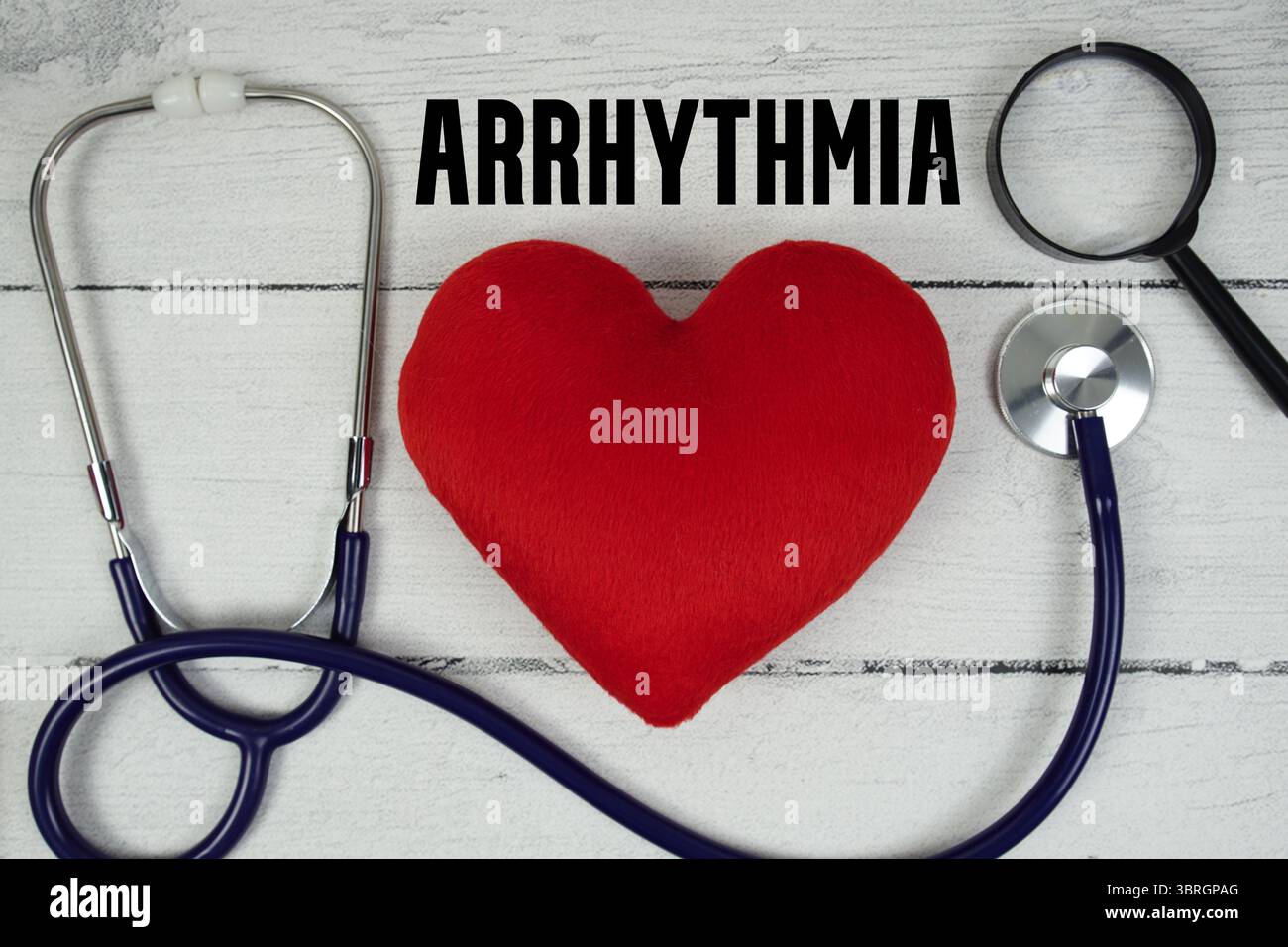 Arrhythmia text with Red heart, Magnifying glass and Medical Stethoscope on wooden background Stock Photo