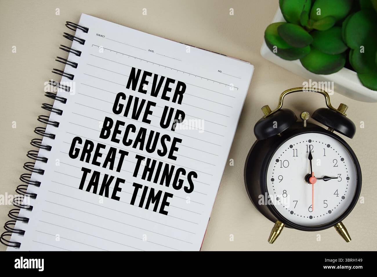 Never give up because great things take time text written on notepad with alarm clock Stock Photo