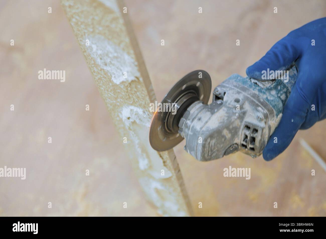A construction worker cutting a tile using grinder round the ceramic disc Stock Photo