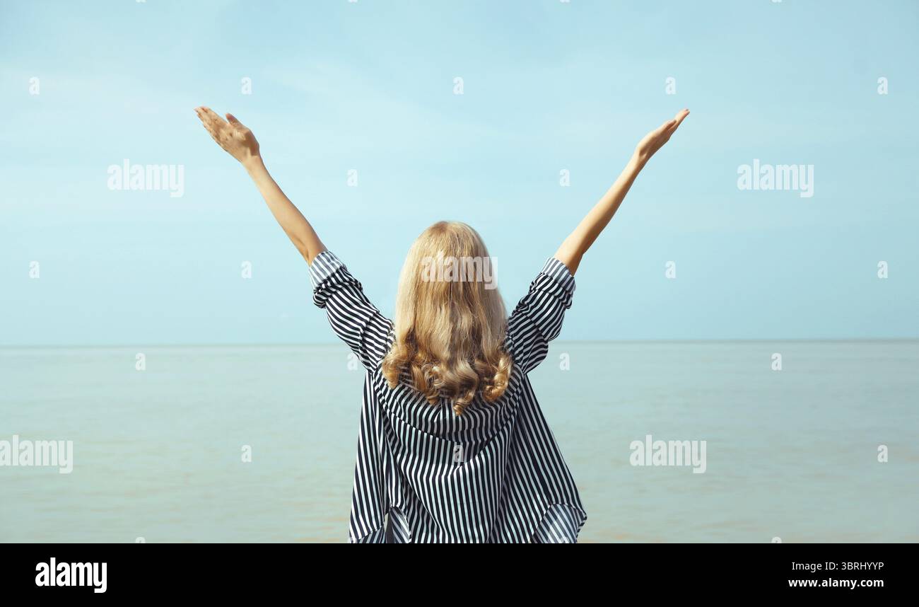 Summer vacation, happy young woman raising her hands up on the beach on ...
