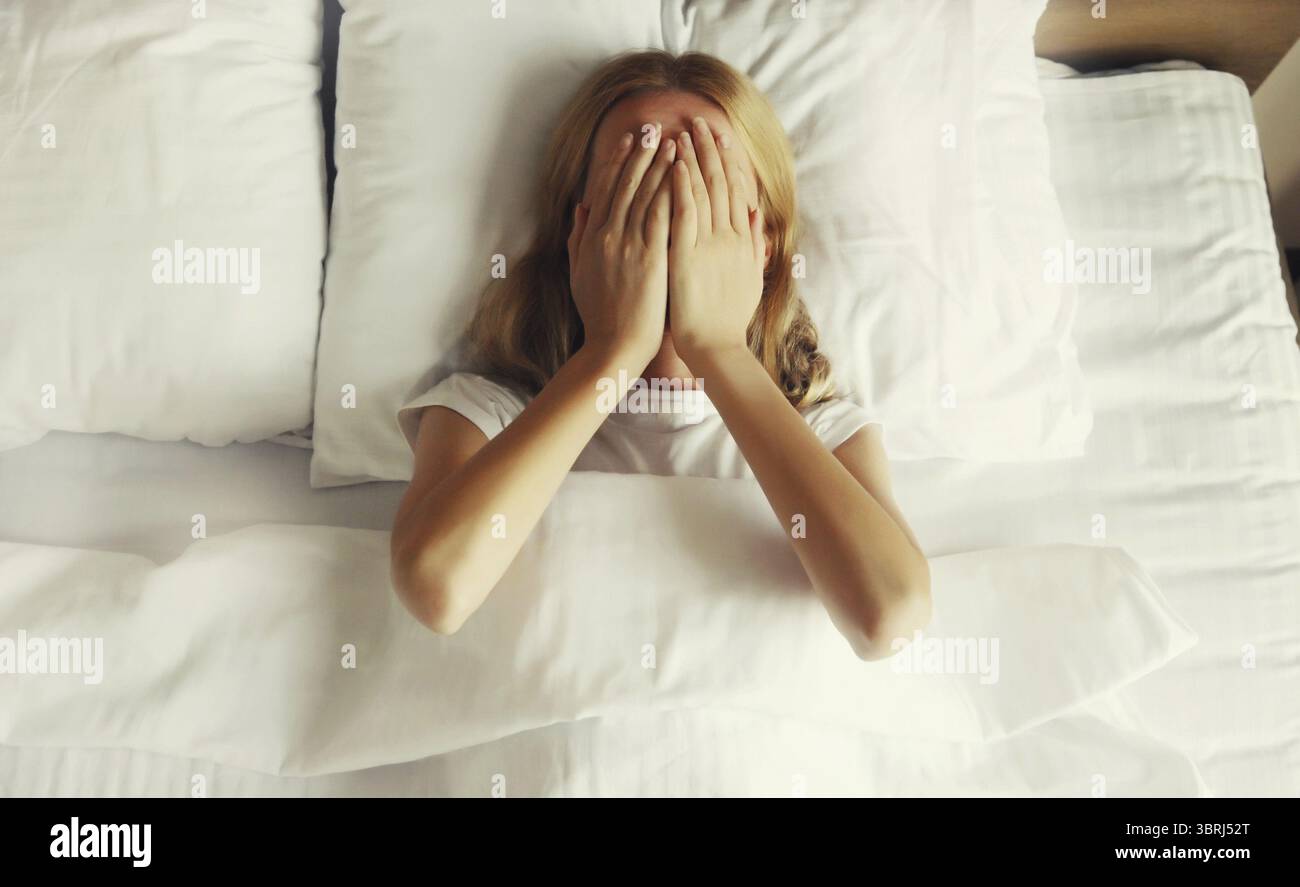Upset sad crying woman covering her eyes with her hands lying on the ...