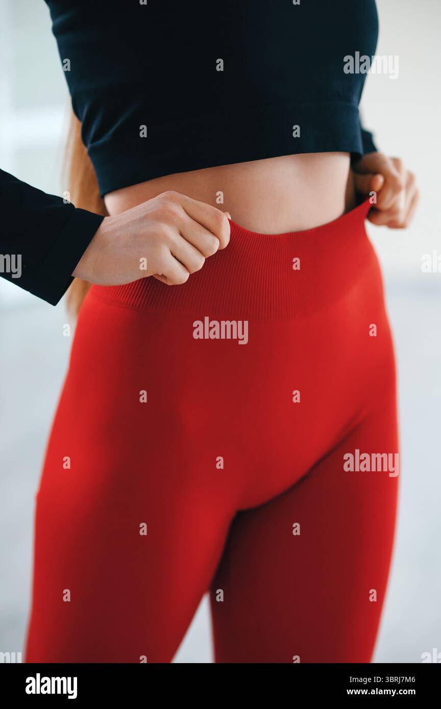 Close up view of female model posing at white studio background and demonstrating comfortable activewear. Front view of perfect fit body in slim black Stock Photo