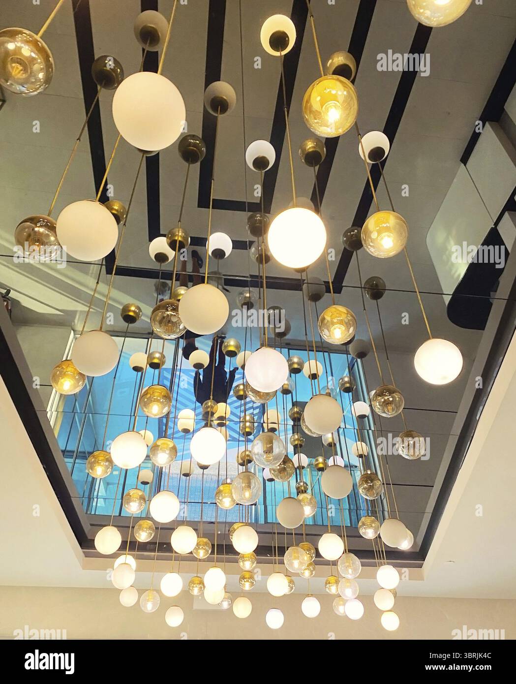 Many hanging lights, pendant round ball-shaped lamps on the mirror ceiling, interior decor Stock Photo
