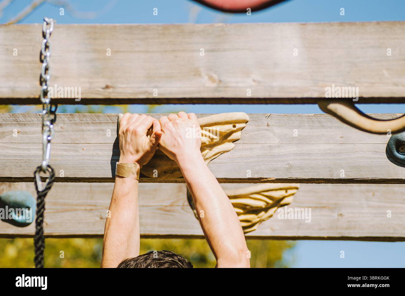 athlete developing powerful grip strength on a wooden climbing hold outdoors Stock Photo