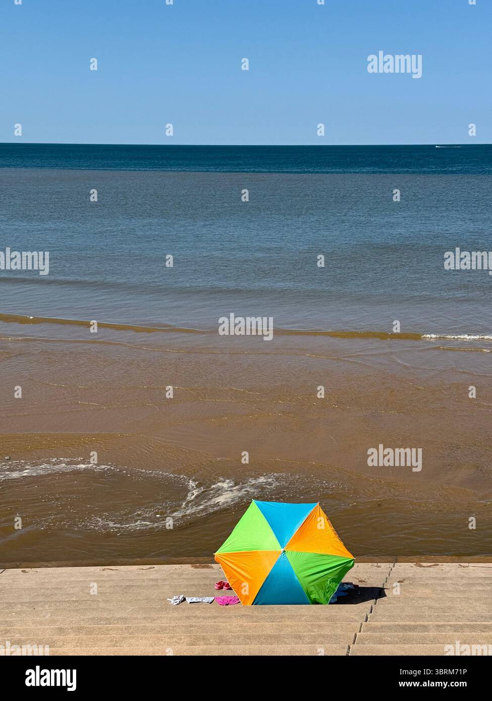 Colourful sun shade on the steps of the sea wall at Blackpool as the tide comes in - Smartphone Captured Stock Image