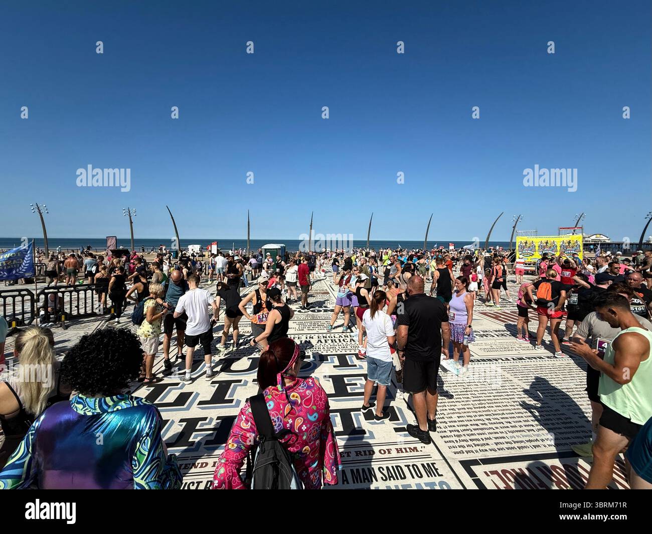 Runners gathering for the start of a race along the promenade. The Comedy Carpet mosaic on Blackpool promenade - Smartphone Captured Stock Image