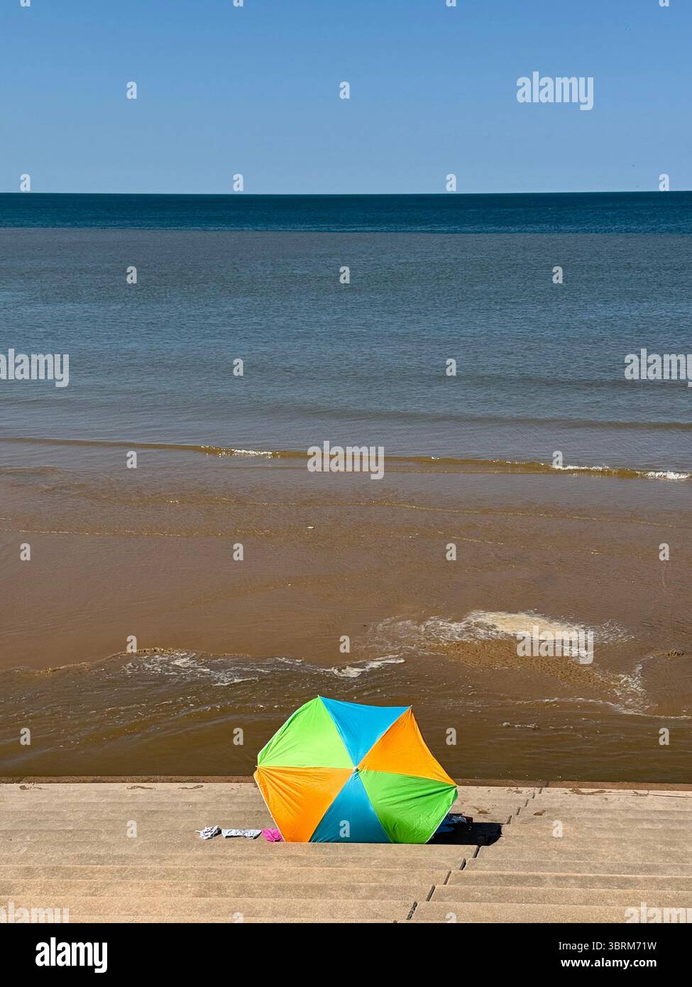 Colourful sun shade on the steps of the sea wall at Blackpool as the tide comes in - Smartphone Captured Stock Image