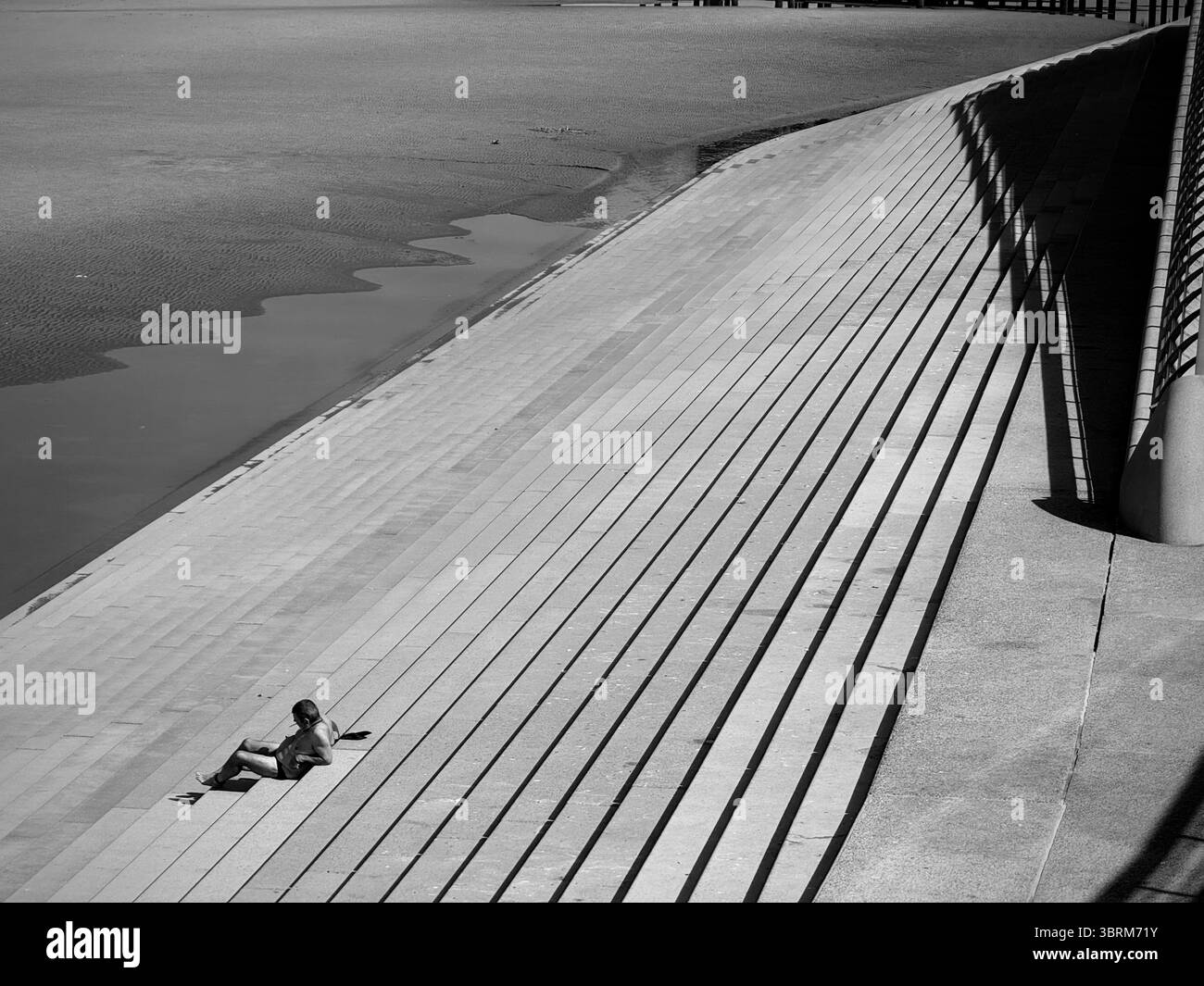 Shadows on the steps of the sea wall at Blackpool with a single figure - Smartphone Captured Stock Image