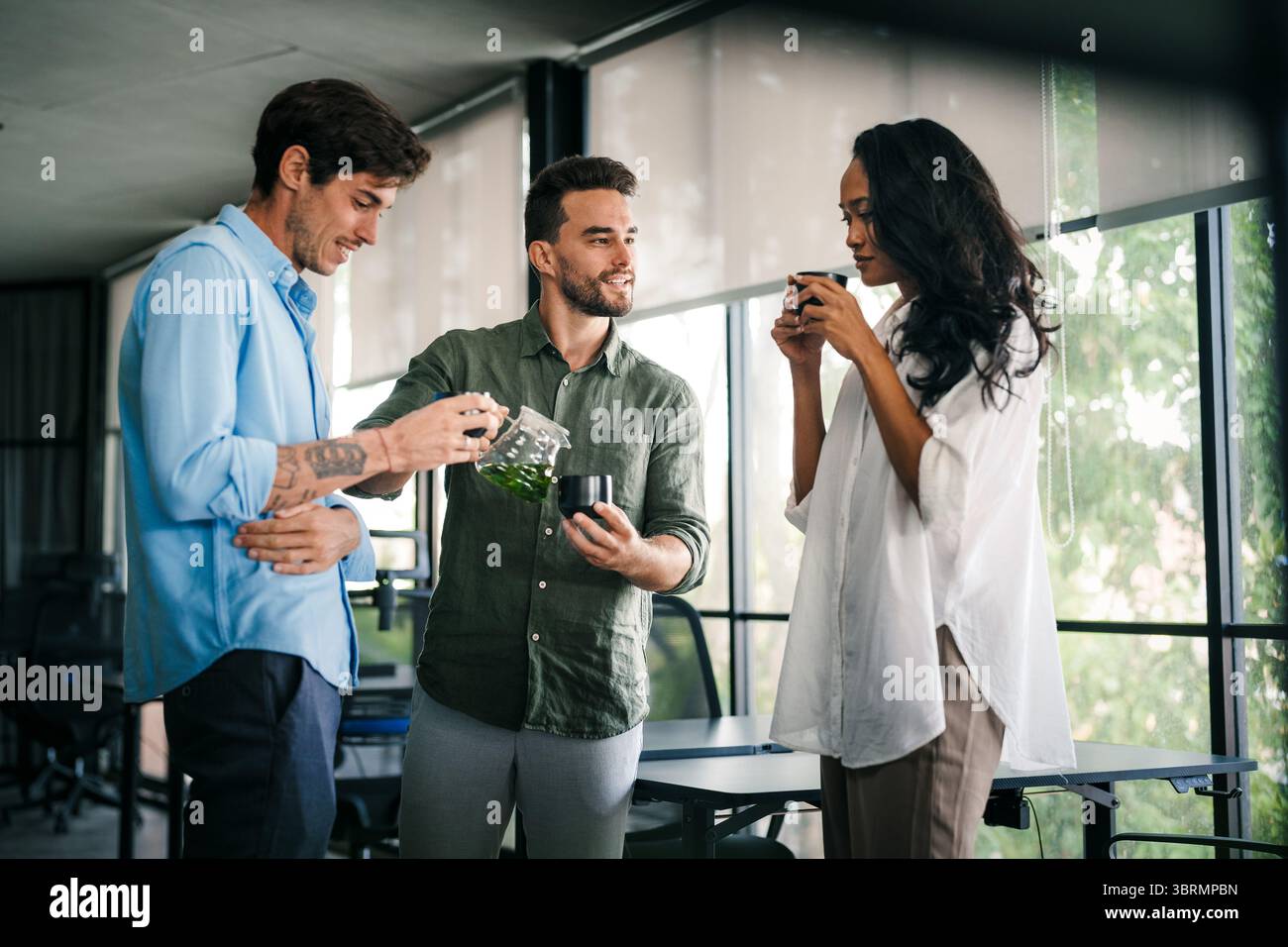 Happy creative diverse colleagues having fun while talking and drinking coffee, tea in working break Stock Photo