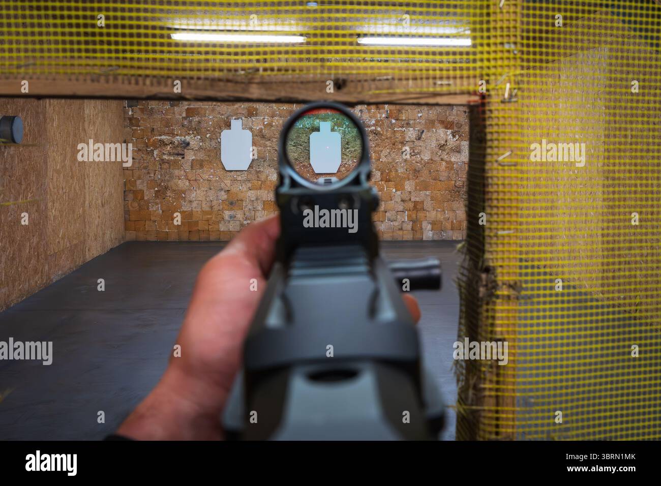 First-person view: a shooter aims a modern carbine with a red dot sight ...