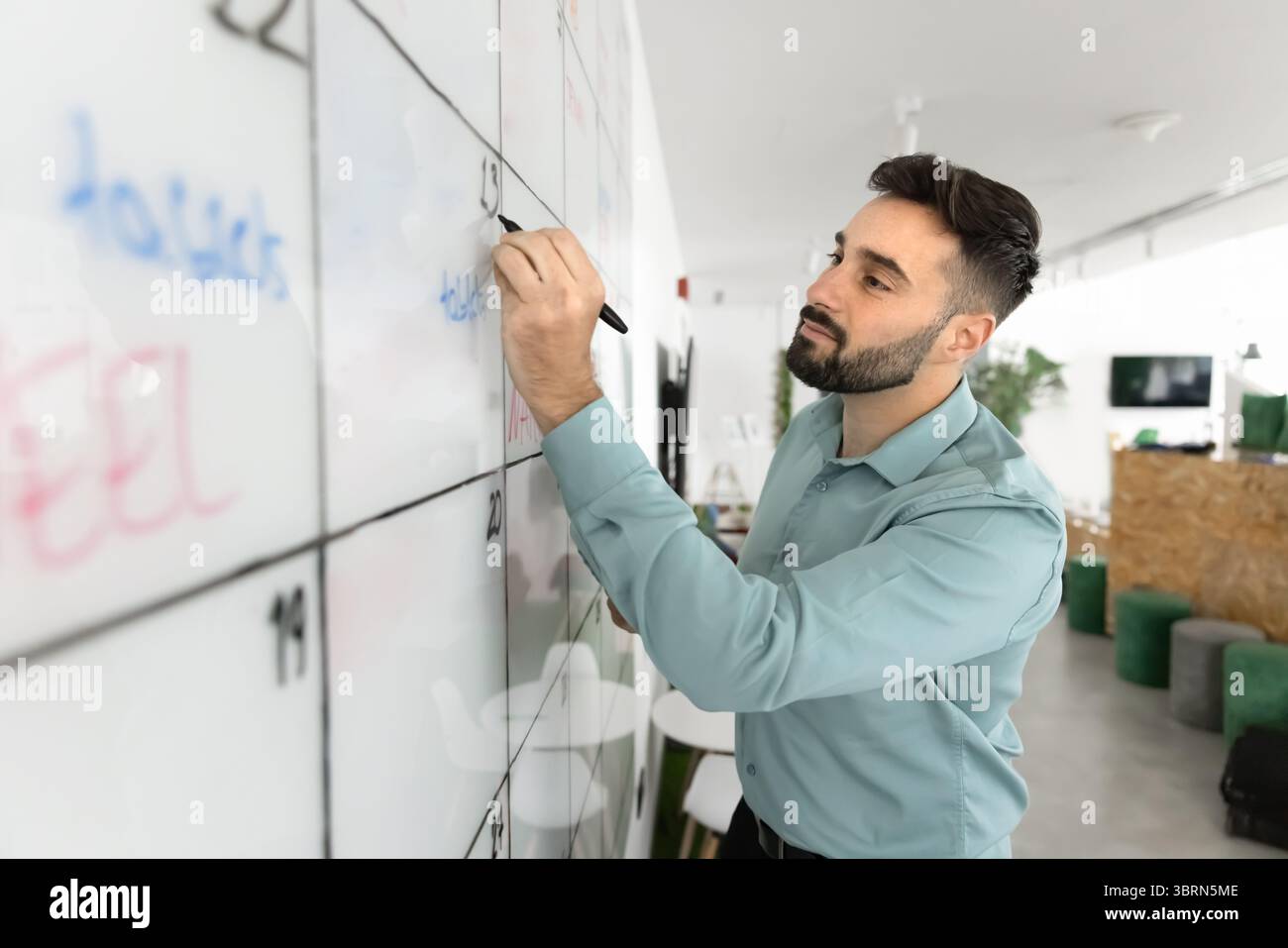 Young Hispanic man writing on large whiteboard Stock Photo
