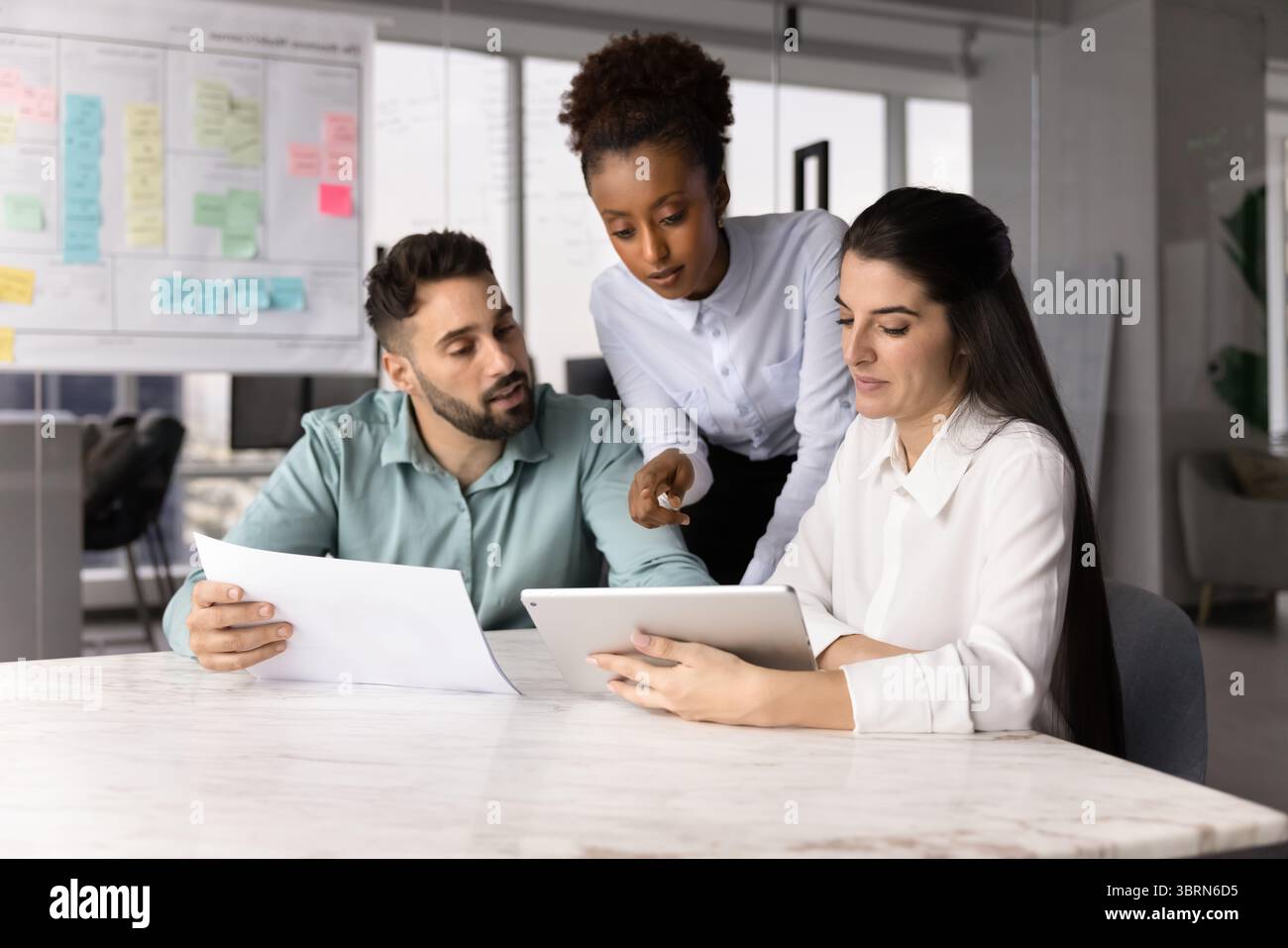 Colleagues working on joint project using digital and print resources Stock Photo