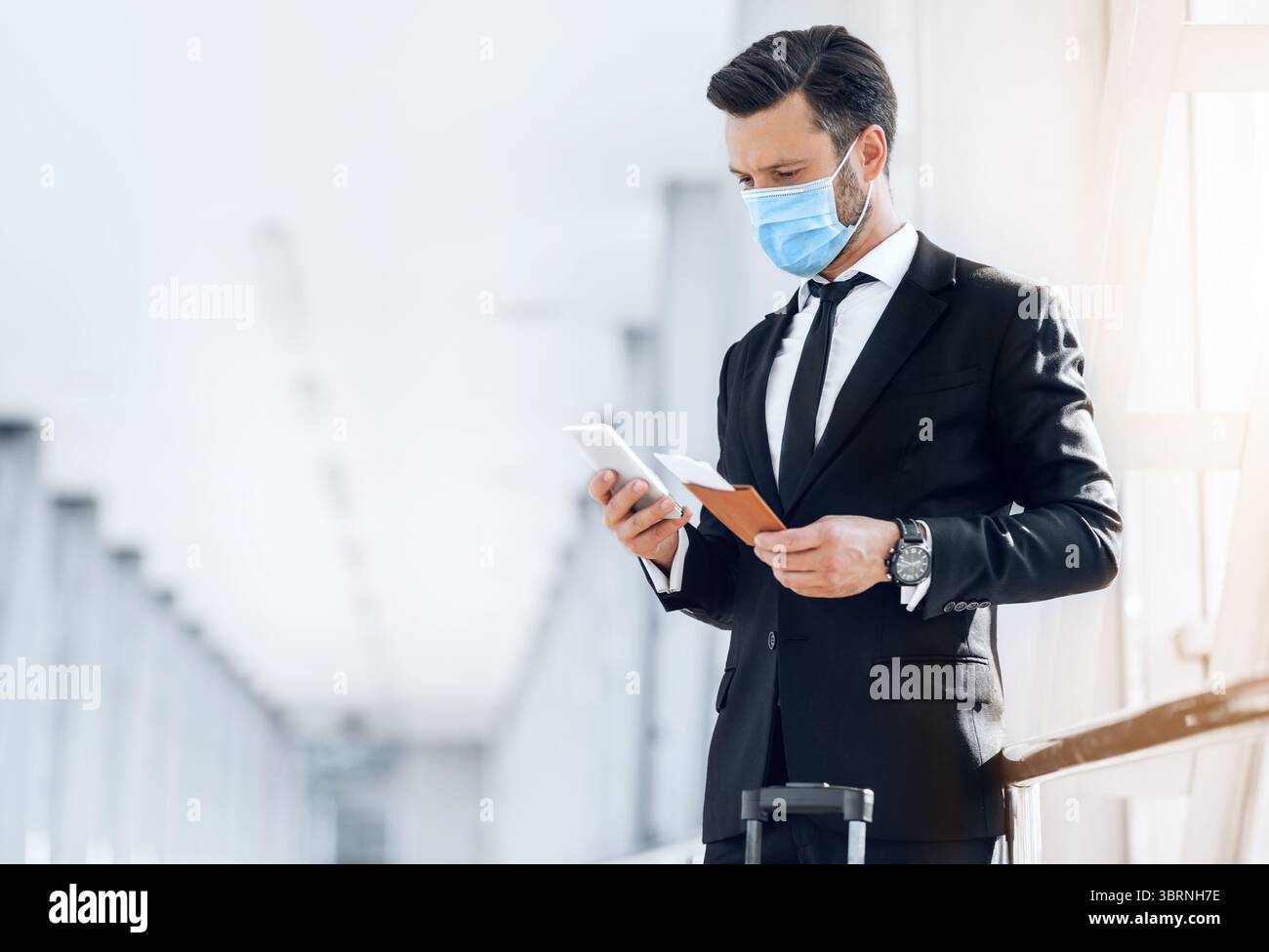 Entrepreneur in face mask using phone while waiting for flight Stock Photo