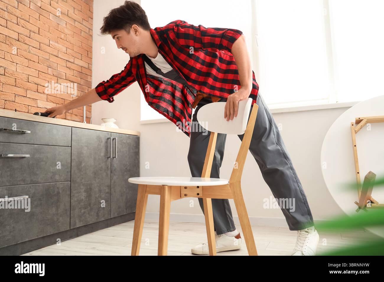 Male worker assembling chair in kitchen Stock Photo