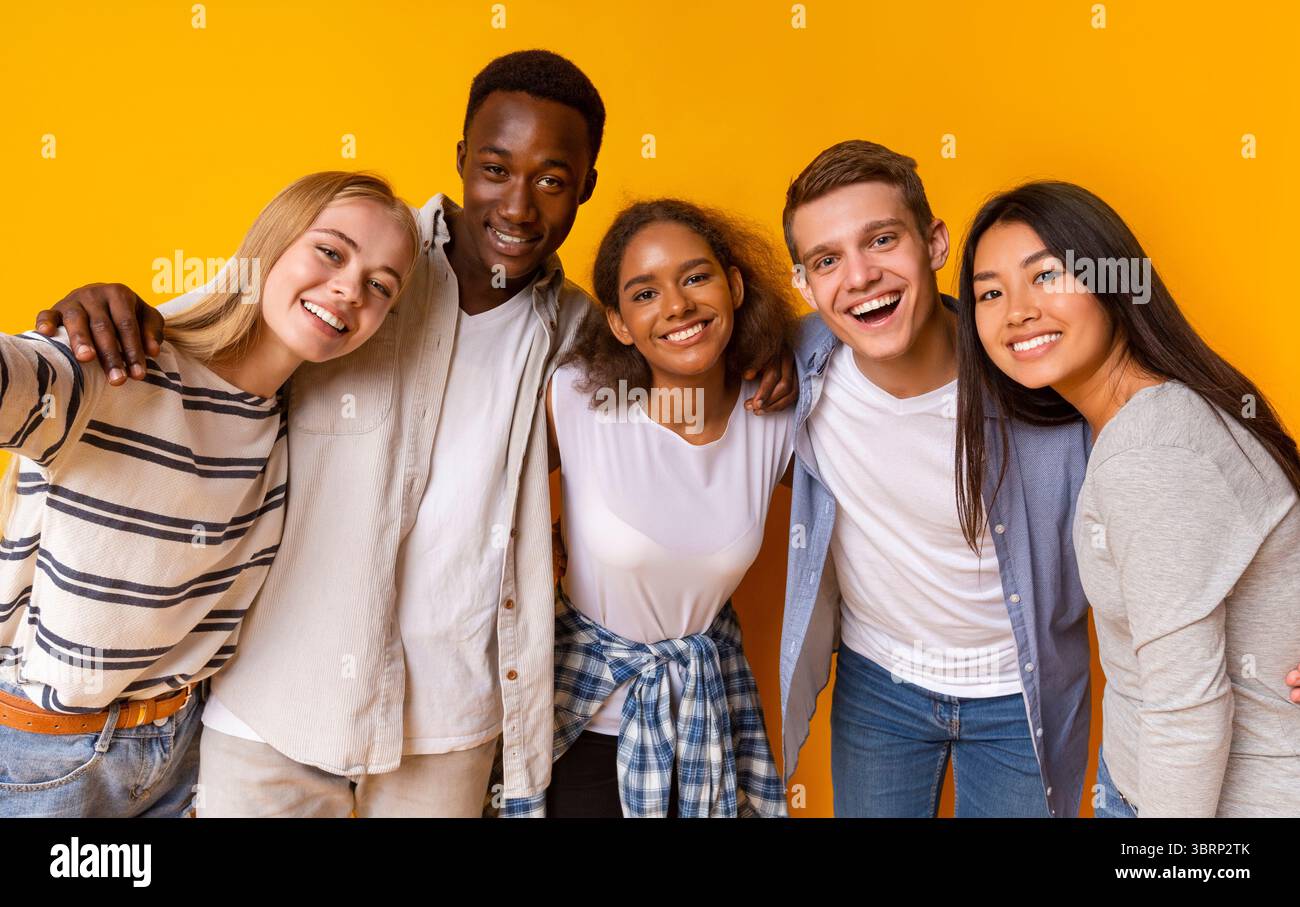 Friendly international students taking selfie over yellow background Stock Photo