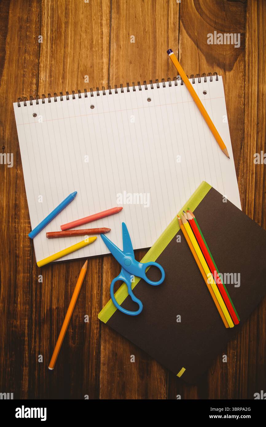 Flat design scene is showing spiral notebook is lying on wooden tabletop with crayons and pencils Stock Photo