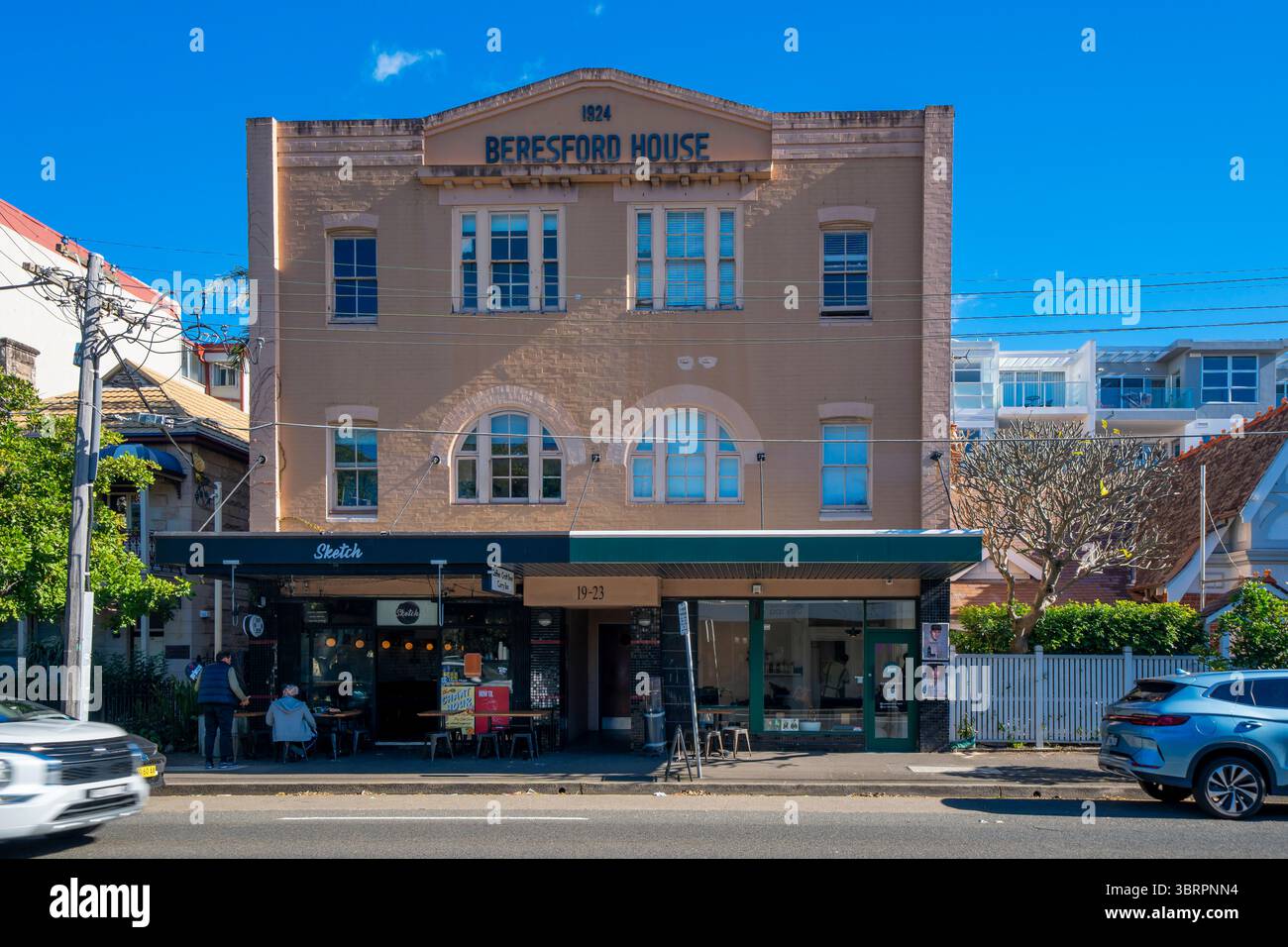 A 1920's apartment block in Manly, New South Wales, Australia with a busy ground floor coffee shop on a weekday morning Stock Photo