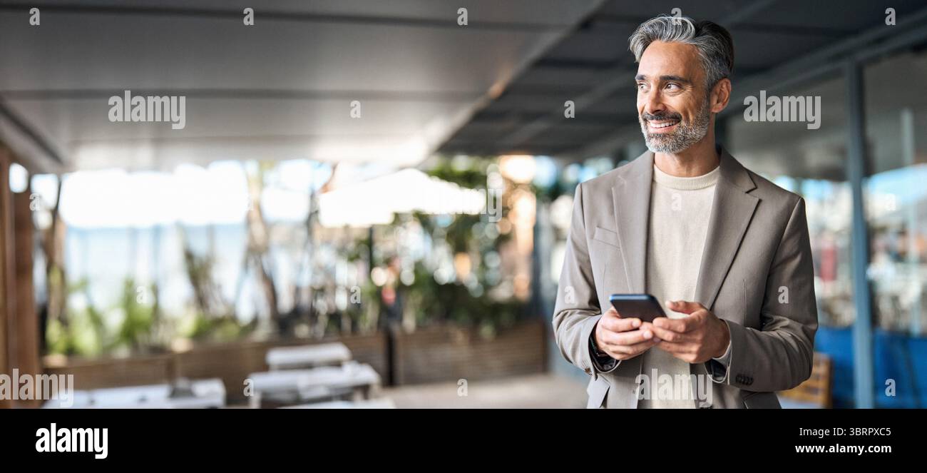 Happy mature business man using phone outdoors. Copy space for ads. Stock Photo