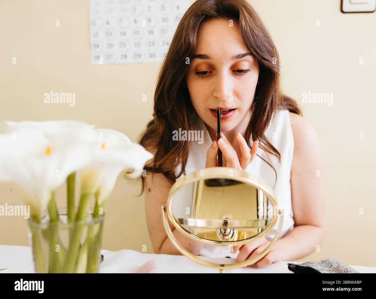 Young woman doing her makeup with a small handheld mirror Stock Photo