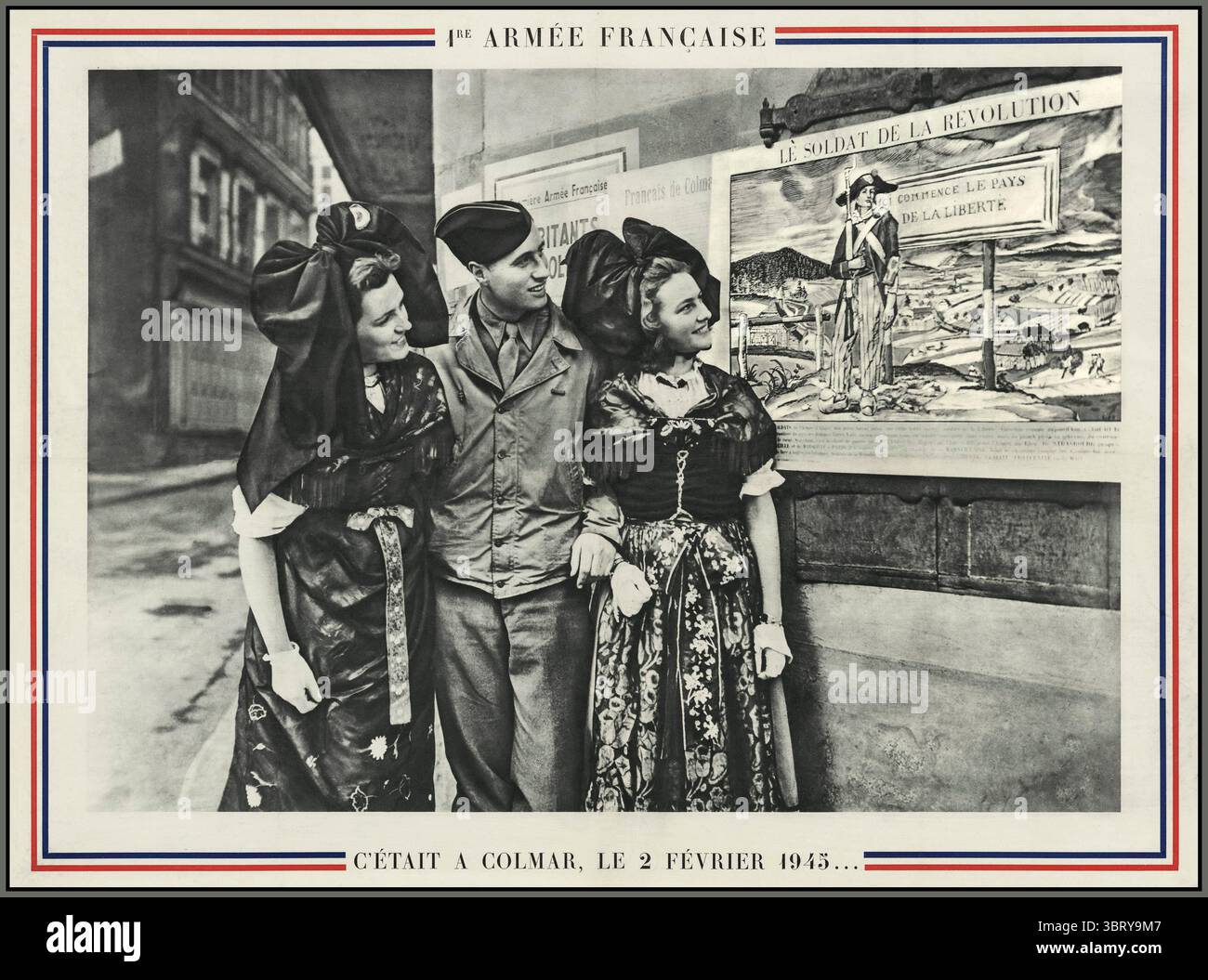 First French Army WW2 - It was in Colmar on 2 February 1945  1re armee francaise. C'etait a Colmar, le 2 fevrier 1945...ALSACE COLMAR Photograph of a soldier and two women in Alsatian costume looking at proclamations posted on the walls of the city of Colmar with big smiles on their faces. First French Army - in Colmar on 2 February 1945. Première armée française : c'était à Colmar le 2 février 1945.- S.l. : Ed. Braun, [1945] - Soldat de la 1ère Armée entre deux alsaciennes Stock Photo