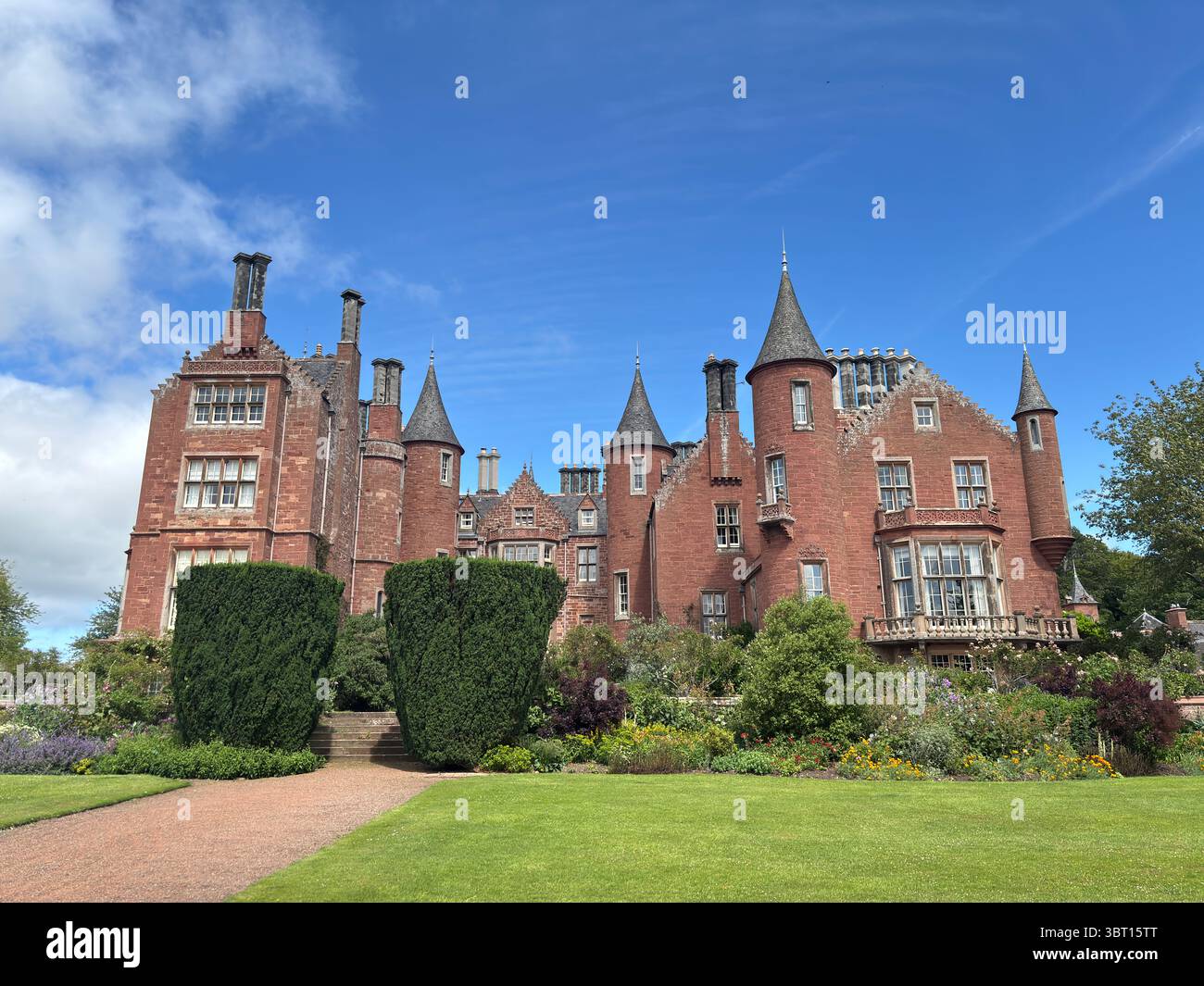 Tyninghame House, a red-sandstone Scots baronial mansion near the River Tyne estuary, set in expansive gardens—built in 1829 over earlier medieval Stock Photo