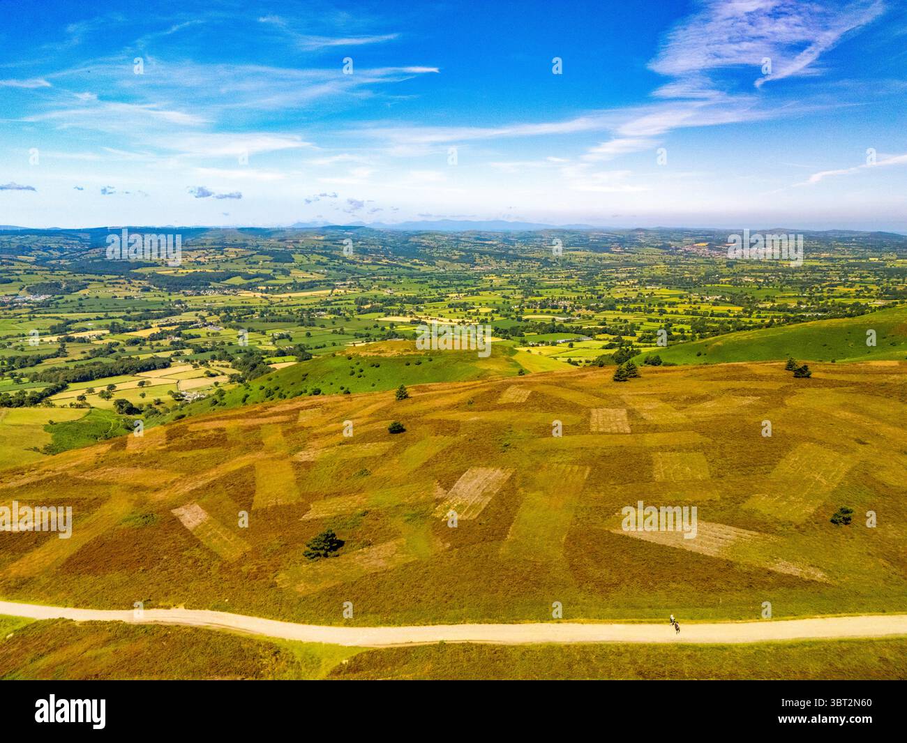 An aerial view shows a landscape with an upland trail and  two people are walking, the landscape is a mix of green and brown with the Vale of Clwydian Stock Photo
