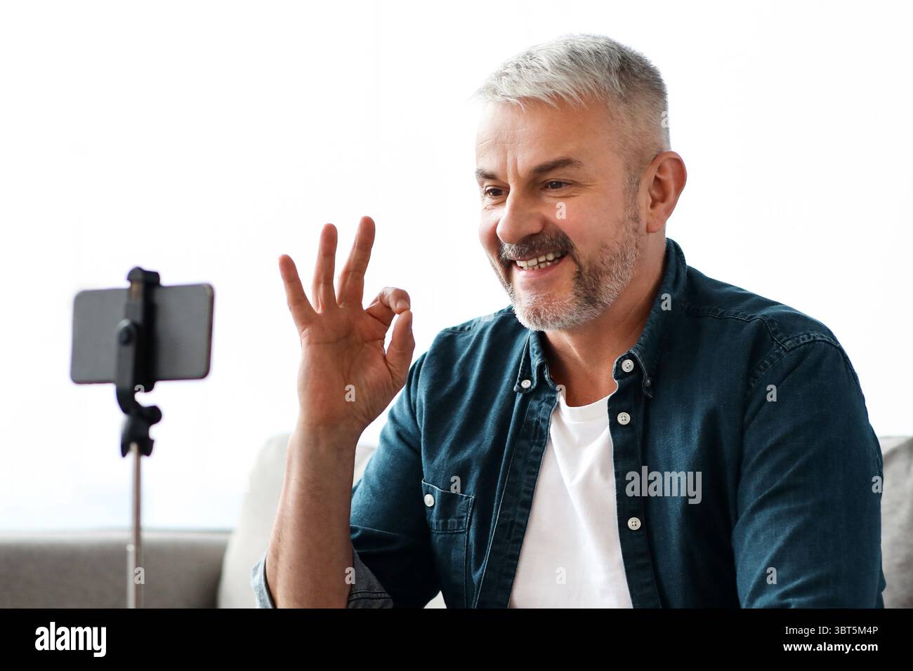 Smiling senior man vlogger broadcasting from home Stock Photo
