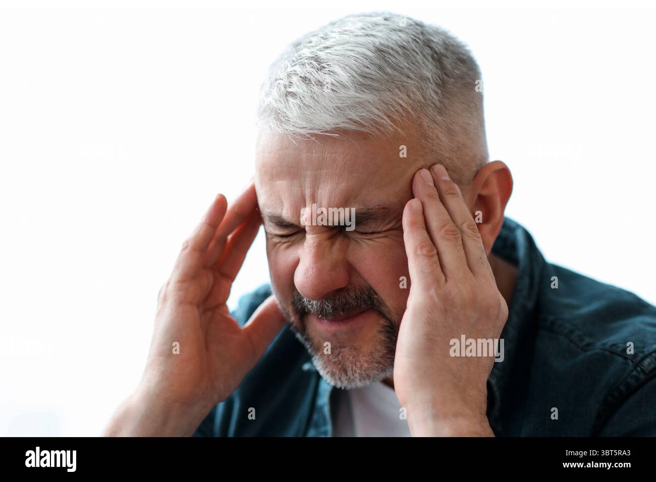 Closeup of mature grey-haired man suffering from headache Stock Photo