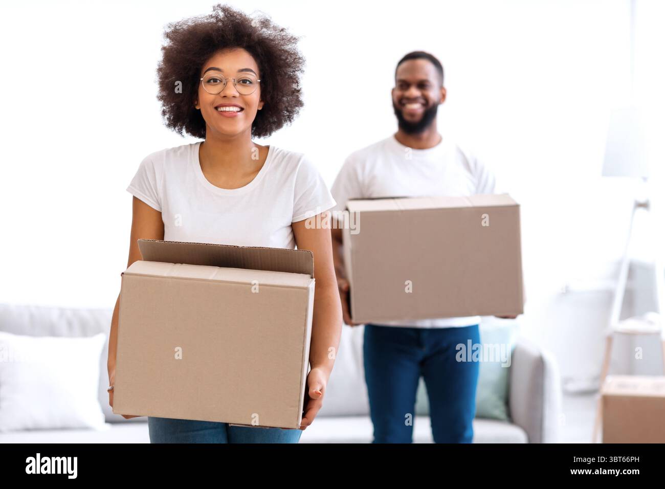 Black Couple Moving Carrying Packed Cardboard Boxes Into New Home Stock Photo