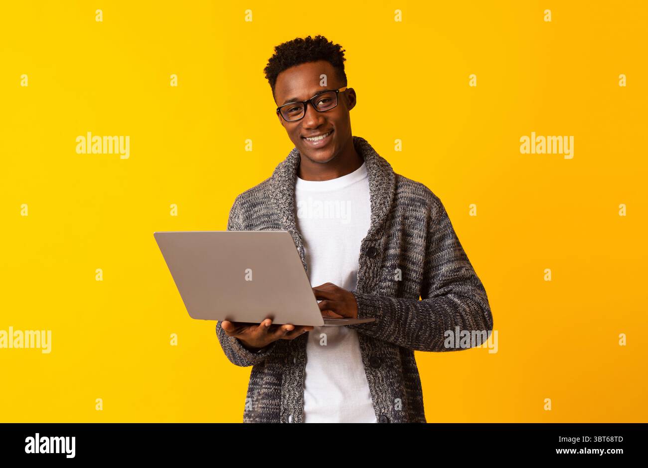 Handsome young african man using laptop on yellow Stock Photo