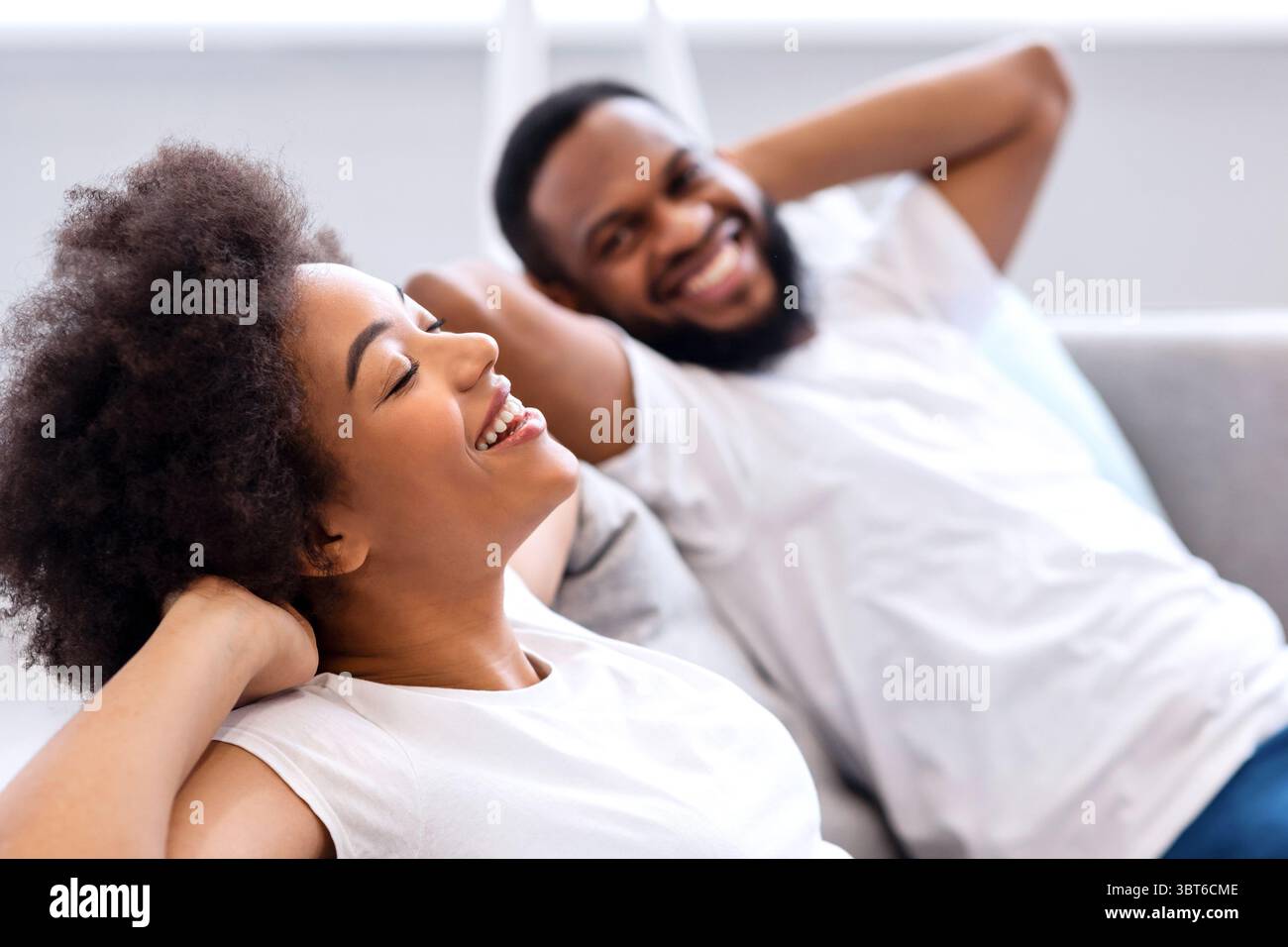 Happy Black Couple Resting Sitting On Sofa At Home Stock Photo