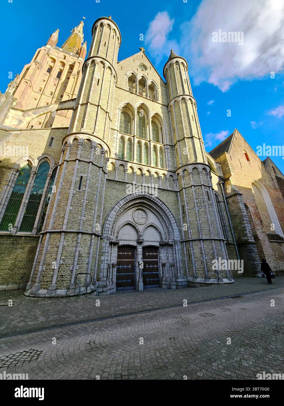 The Church of Our Lady in Bruges, Belgium, under a vivid blue sky, showcasing its historic Gothic architecture and monumental facade. - Smartphone Captured Stock Image