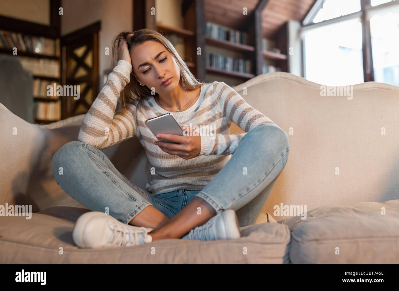 Worried confused lady using cellphone, looking at screen Stock Photo