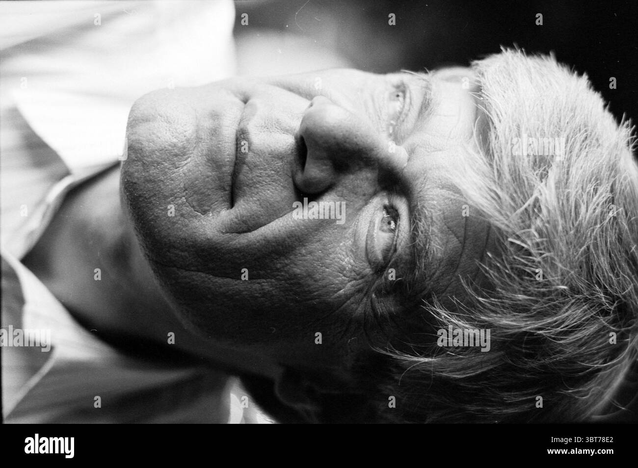 Mr Giebels chairman of tennis Haarlem Haarlem The Netherlands, Whizgle News, Dutch Desk, The Netherlands, 1950 - 2000 on 19-08-1991. These topics appear in the image. The scene features a middle-aged man, captured in a portrait-style composition. He has light gray hair, styled in a slightly tousled manner, which contrasts against the darker background. His skin shows signs of age, with subtle wrinkles adding character to his face. The man gazes upward, with a contemplative expression that conveys a sense of introspection or reflection. His eyes are a striking feature, drawing attention with th Stock Photo