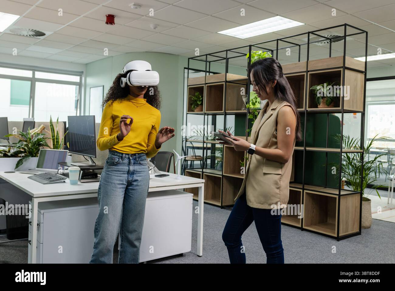 Diverse coworkers testing VR headset and using smartphone in open-plan office, copy space Stock Photo
