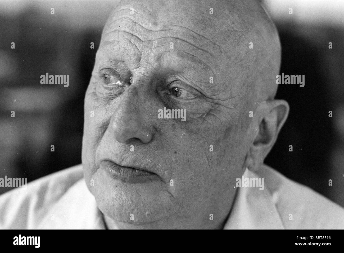 Hans Paalman former director of the Stedelijk Museum [Schiedam], Whizgle News, Dutch Desk, The Netherlands, 1950 - 2000 on 02-08-1994. The image shows these topics. The scene depicts an older man with a smooth, bald head, showcasing deep wrinkles on his forehead and around his eyes, which convey a sense of wisdom and experience. His expression is contemplative, evoking a profound mood that suggests he is lost in thought. The skin tone is fair, with subtle variations highlighting the contours of his face. His eyes are a focal point, filled with a mixture of light and shadow, adding depth and em Stock Photo