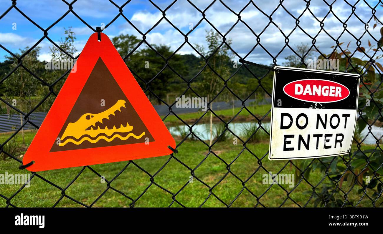 Warning signs on fence around crocodile holding pond, East Russell, near Babinda, Cairns, Queensland, Australia. No PR - Smartphone Captured Stock Image