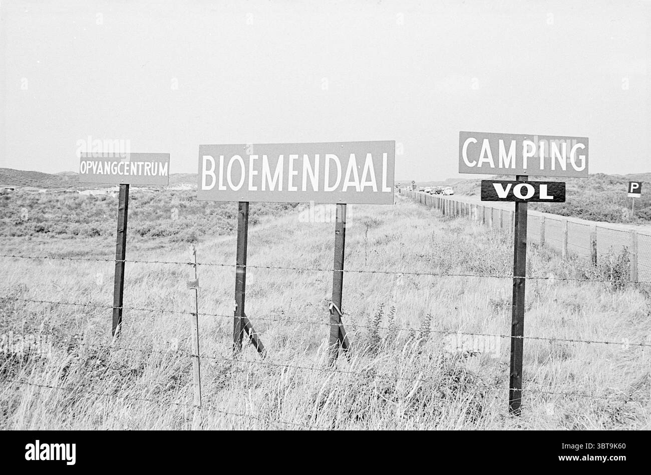 Amsterdam children on holiday Children kid children's homes children's party children's, Whizgle News, Dutch Desk, The Netherlands, 1950 - 2000 on 26-07-1967. The image includes these topics. The scene features an expansive view of a road bordered by grassy fields that stretch out in both directions. In the foreground, several signs stand tall on wooden posts, their bright colors contrasting with the muted tones of the landscape. The largest sign, marked in bold lettering, identifies a location, while neighboring signs provide information in a similar format. The setting appears quiet and spar Stock Photo