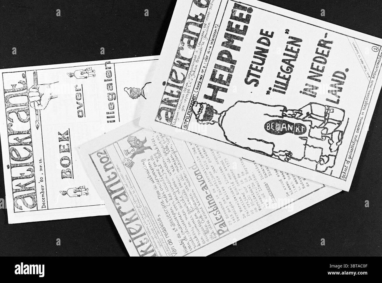 Three copies of the 'Aktiekrant', Whizgle News, Dutch Desk, The Netherlands, 1950 - 2000 on 02-12-1980. The image contains these topics. The scene presents several sheets of paper arranged haphazardly, their surfaces filled with illustrations and bold, graphic designs. The primary colors are stark black and white, creating a high-contrast and vintage feel. Intricate illustrations of people and objects are scattered across the pages, some depicting stylized figures, while others feature abstract shapes. The overall arrangement of the papers suggests a casual, perhaps hurried usage, hinting at a Stock Photo