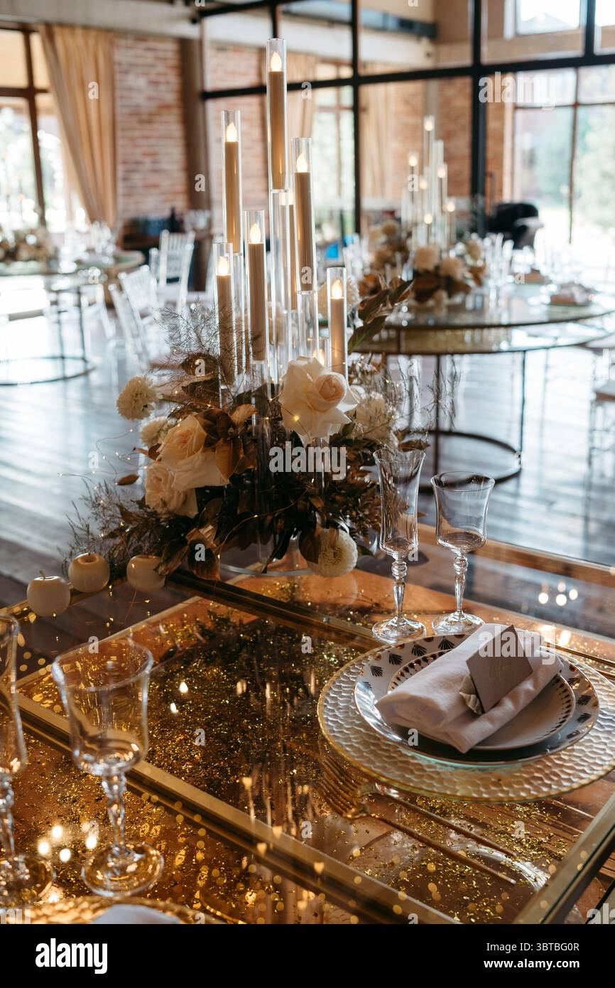 A sophisticated table arrangement with candles, white roses, and glassware, perfect for a formal event or special occasion, highlighting elegance and Stock Photo
